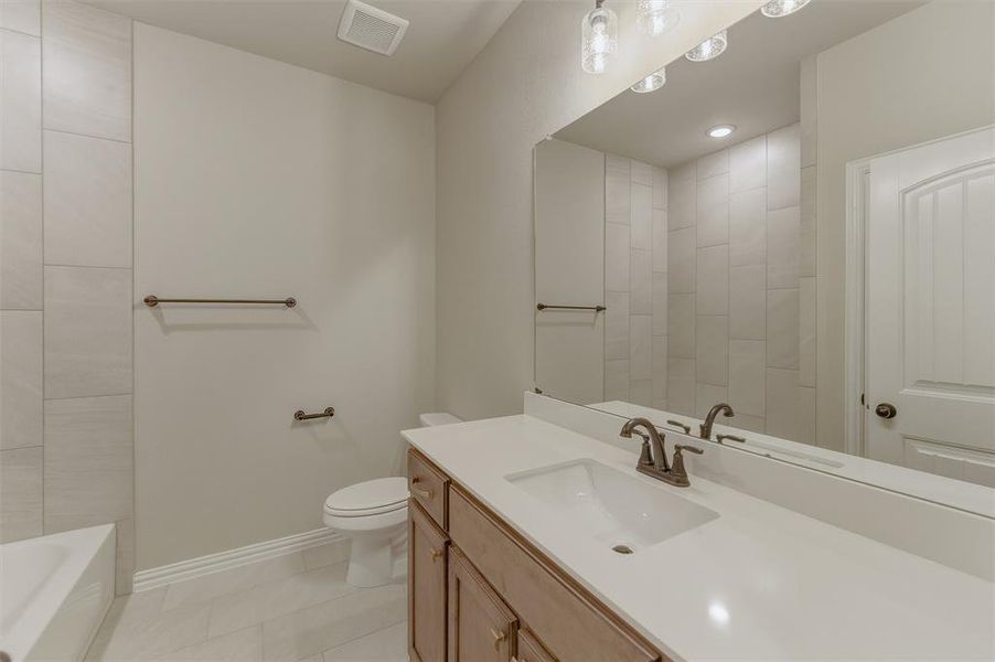 Bathroom vanity featuring a single basin sink, white countertop, and wood-finish cabinetry