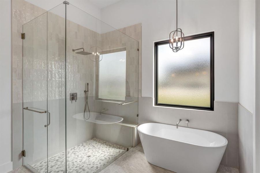 Bathroom featuring a Seperate walk in shower with glass surround, a freestanding tub, a chandelier, and tile walls