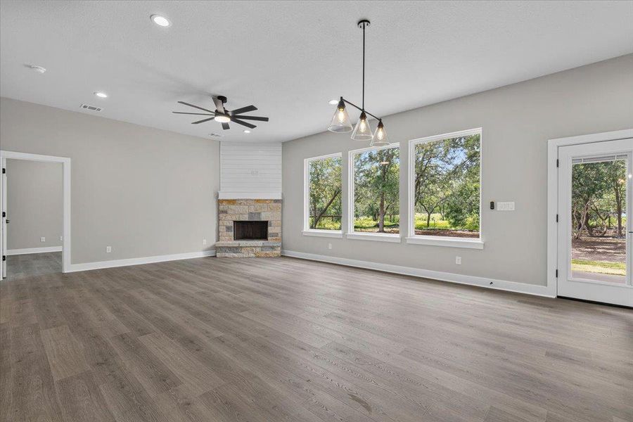A spacious common area boasts wood flooring, a charming stone fireplace, and ample natural light from numerous windows and a glass-paneled door. A spacious common area boasts wood flooring, a charming stone fireplace, and ample natural light from numerous windows and a glass-paneled door.