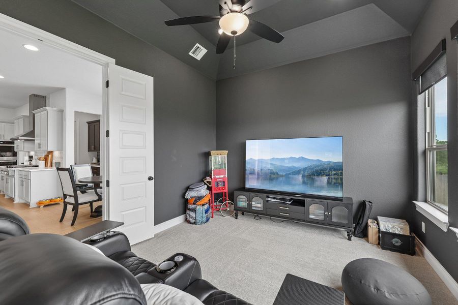 Carpeted entertainment space with vaulted ceilings and a ceiling fan light fixture