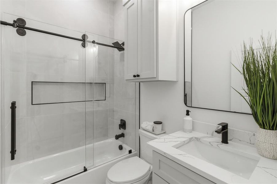 Bathroom featuring a built-in tub with a sliding glass shower door and matte black fixtures