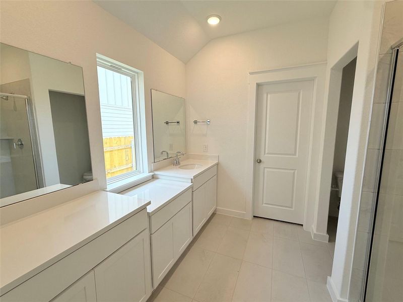 Bathroom featuring a stall shower, vanity, tile patterned floors, vaulted ceiling, and recessed lighting Bathroom featuring a stall shower, vanity, tile patterned floors, vaulted ceiling, and recessed lighting