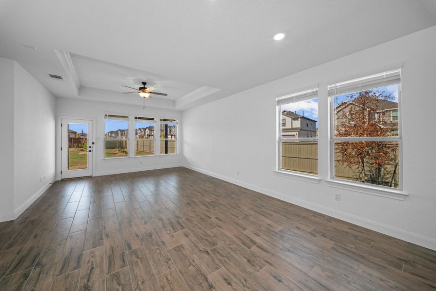 Spare room with a raised ceiling, a ceiling fan, and dark wood-type flooring Spare room with a raised ceiling, a ceiling fan, and dark wood-type flooring