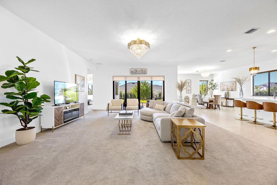 Living area with plenty of natural light, light colored carpet, a chandelier, and a textured ceiling