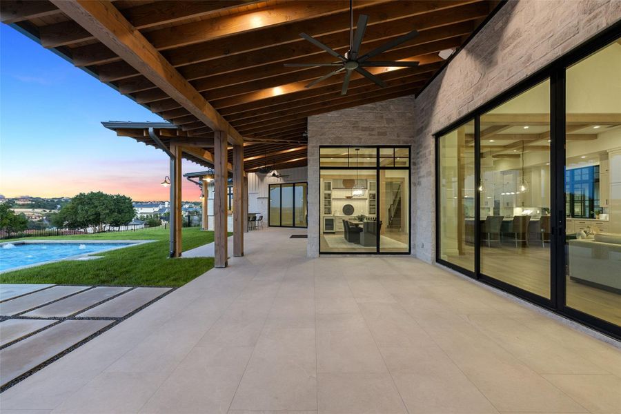 Patio terrace at dusk with a ceiling fan, a patio area, an outdoor pool, and a yard