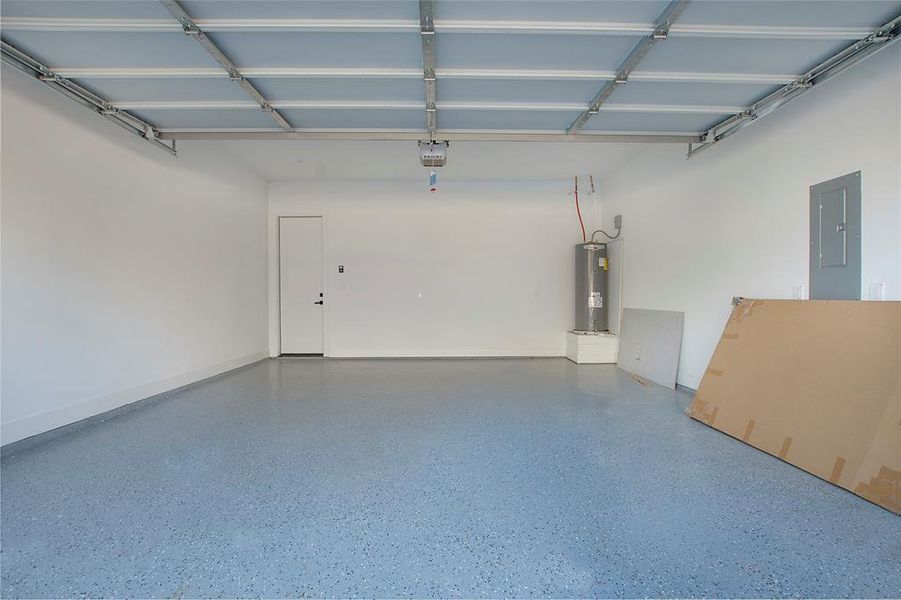 Garage featuring a garage door opener, electric panel, and water heater