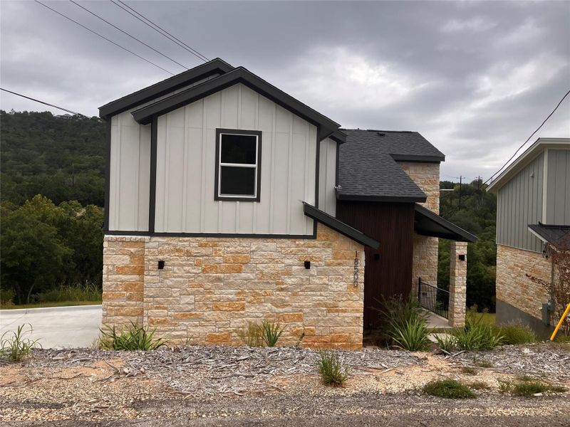 View of home's exterior featuring stone siding, board and batten siding, and a shingled roof