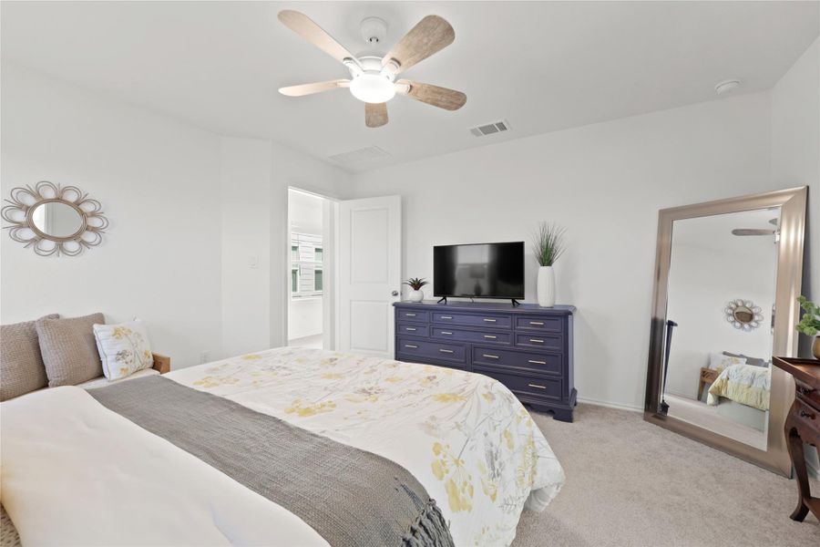 Plush carpeting and crisp white walls create a bright, inviting atmosphere in the primary bedroom, which features a private doorway leading to the spacious ensuite bathroom