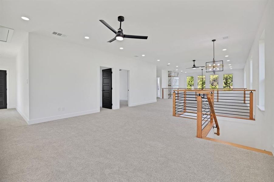 Living room with ceiling fan with notable chandelier and light colored carpet