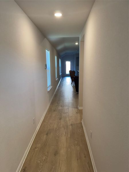 Hallway with lofted ceiling, wood finished floors, and recessed lighting