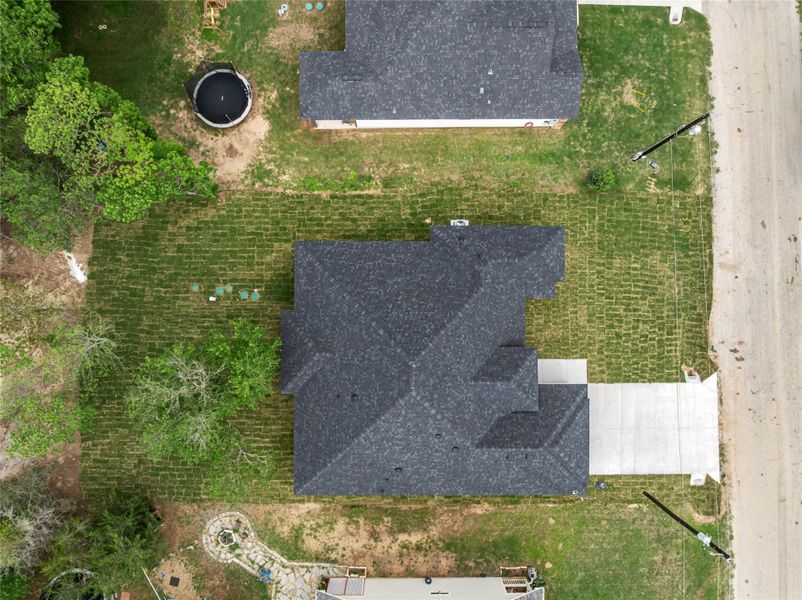 New construction home featuring a dark asphalt shingle roof, established sod landscaping, and a concrete driveway