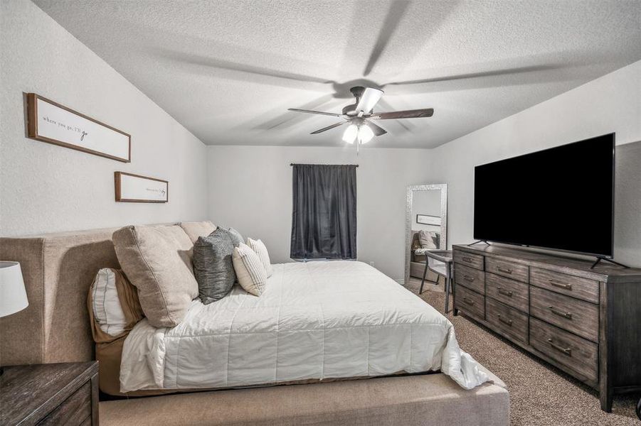 Bedroom featuring ceiling fan, light colored carpet, and a textured ceiling