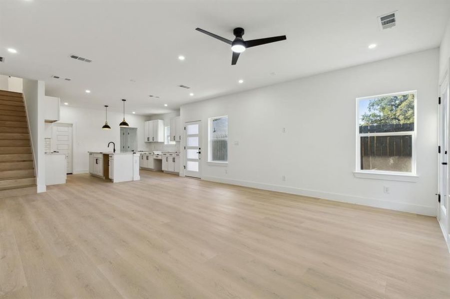 Unfurnished living room featuring ceiling fan, a wealth of natural light, and light wood-type flooring