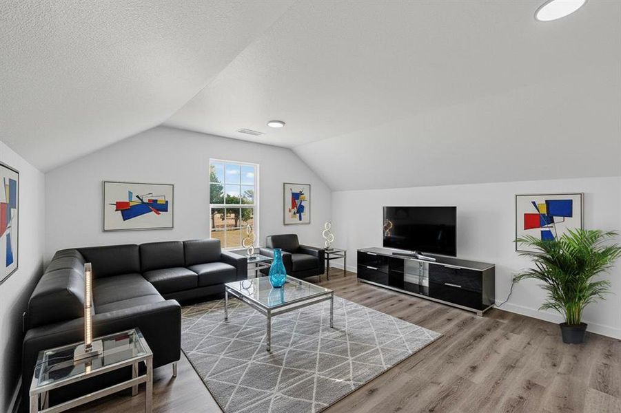 Living area featuring vaulted ceiling, light wood-type flooring, and a textured ceiling