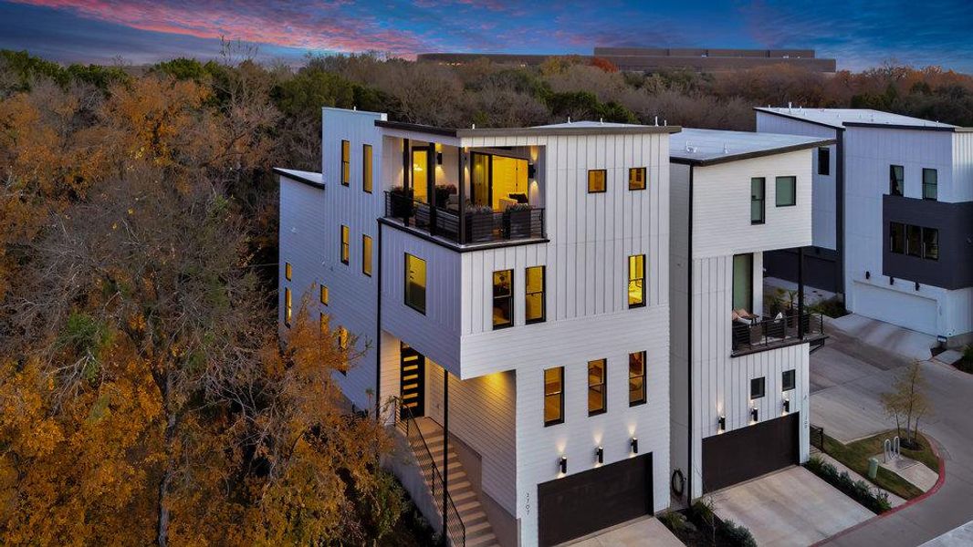 View of front facade featuring board and batten siding, stairs, an attached garage, driveway, and a balcony