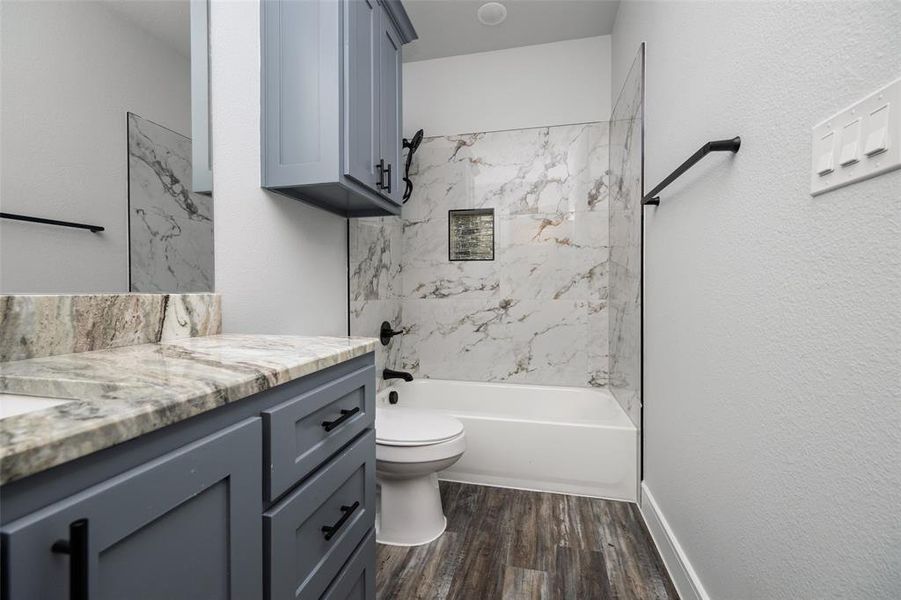 Bathroom featuring  shower combination, vanity, dark wood-type flooring, and a textured wall