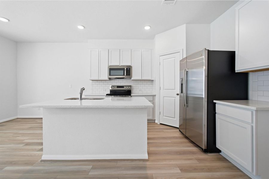 Kitchen with stainless steel appliances, white cabinetry, a kitchen island with sink, light stone countertops, and light wood-style floors Kitchen with stainless steel appliances, white cabinetry, a kitchen island with sink, light stone countertops, and light wood-style floors