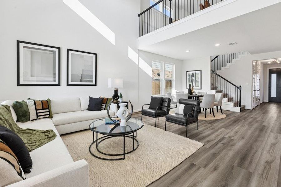 Living area featuring a towering ceiling, wood finished floors, stairs, and recessed lighting Living area featuring a towering ceiling, wood finished floors, stairs, and recessed lighting