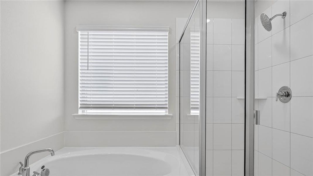 Built-in soaking tub with chrome fixtures, complemented by a separate glass-enclosed shower featuring white tile surround and a rain-style showerhead