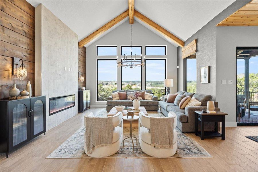 Living area featuring a tiled fireplace, hanging lights, beamed ceiling, and light wood-style flooring