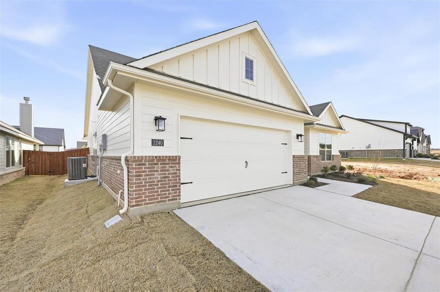 View of property exterior with brick siding, driveway, a garage, and board and batten siding