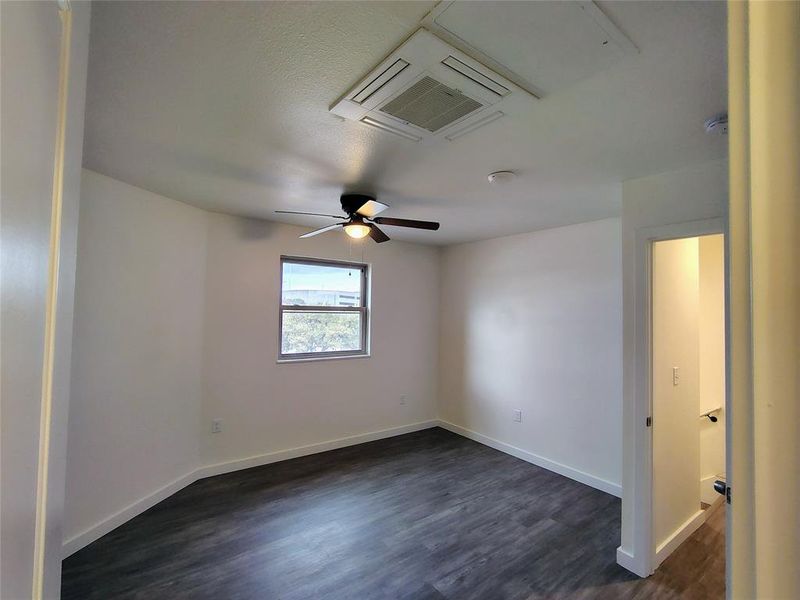 Empty room with ceiling fan and dark hardwood / wood-style flooring