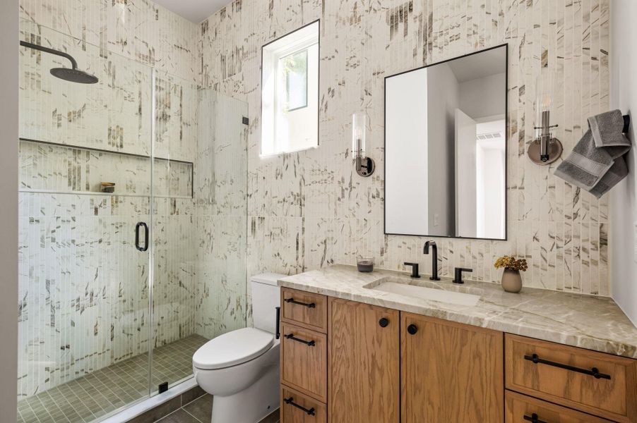 Gleaming stone countertops and a modern glass shower elevate this bathroom design. Gleaming stone countertops and a modern glass shower elevate this bathroom design.