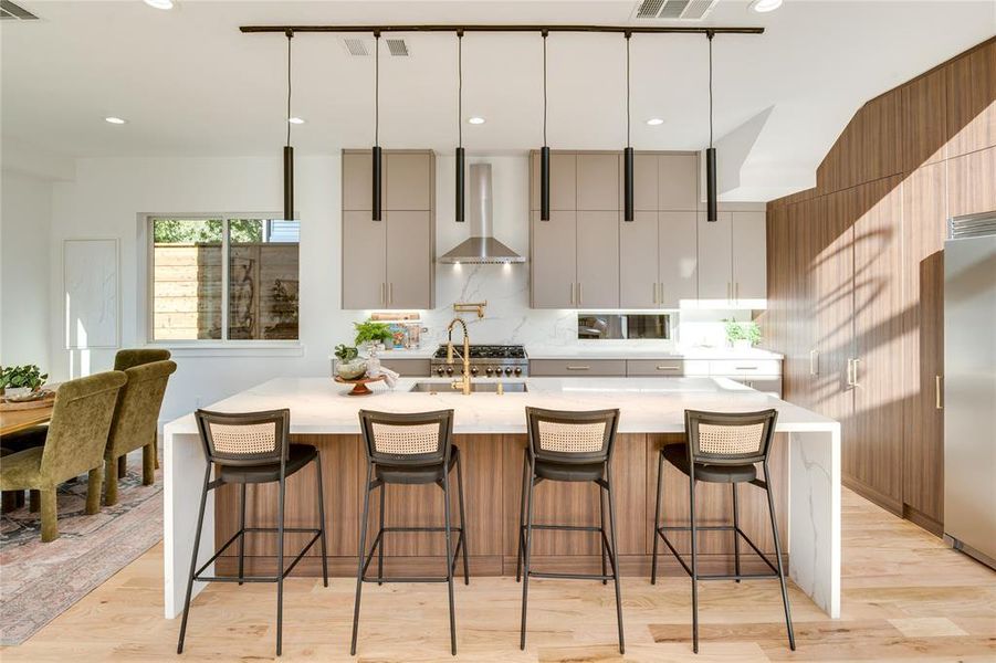 Kitchen featuring a breakfast bar, white cabinets, wall chimney range hood, and light wood-type flooring