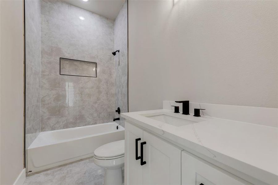 Full bathroom with tile patterned flooring, toilet, tiled shower / bath, and vanity