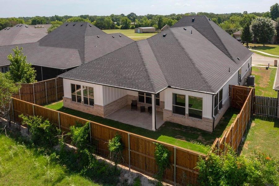 Back of property featuring a patio, brick siding, a fenced backyard, and roof with shingles