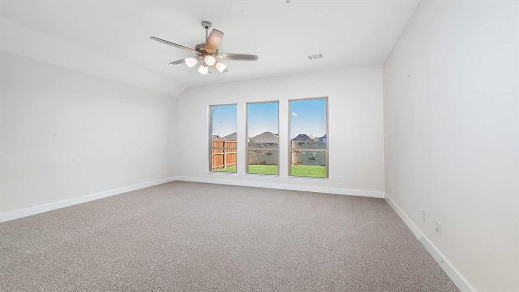 Spare room featuring carpet, ceiling fan, and vaulted ceiling