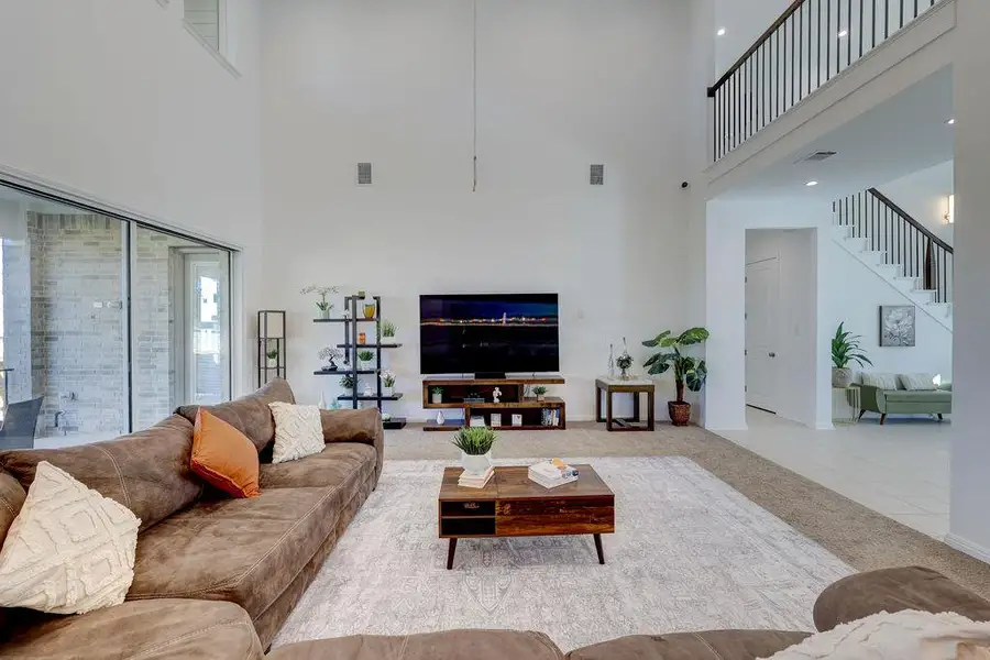 Carpeted living area featuring a towering ceiling, tile patterned flooring, and stairway