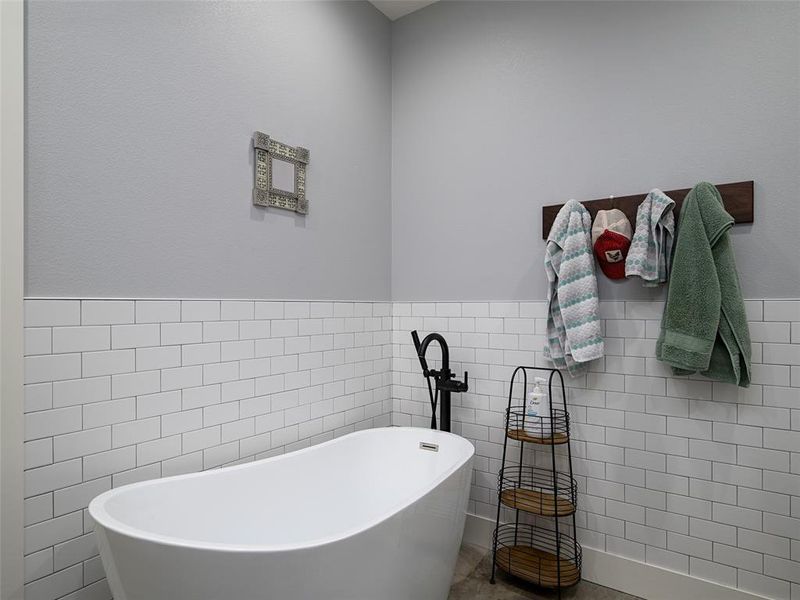 Bathroom with a soaking tub, tile walls, and wainscoting Bathroom with a soaking tub, tile walls, and wainscoting