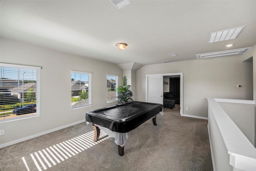Bright and spacious game room with large windows, plush carpeting, and a versatile layout perfect for entertainment.