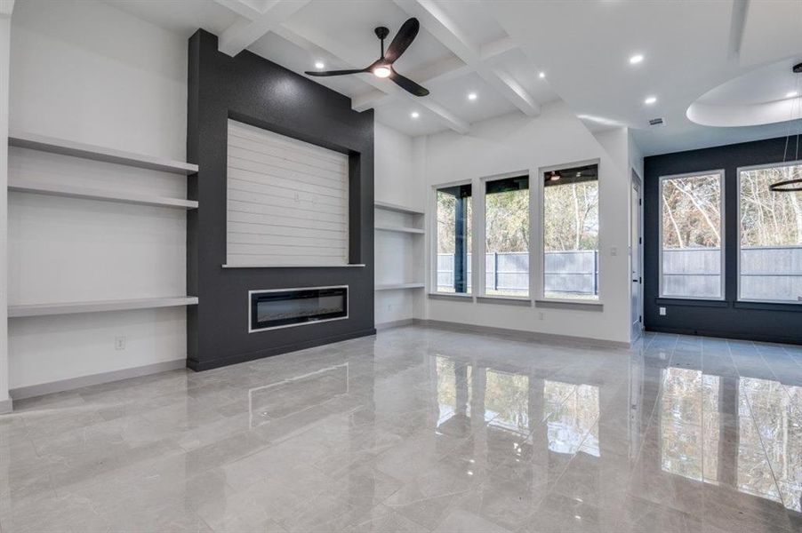 Unfurnished living room featuring beamed ceiling, built in features, and ceiling fan