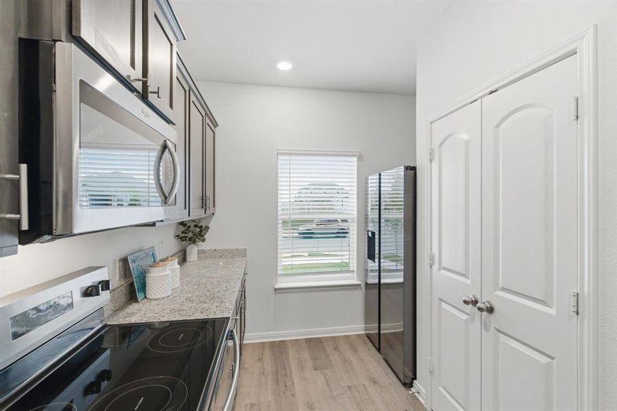 The kitchen features wood plank flooring, stainless steel appliances, granite countertops, and dark wood cabinetry