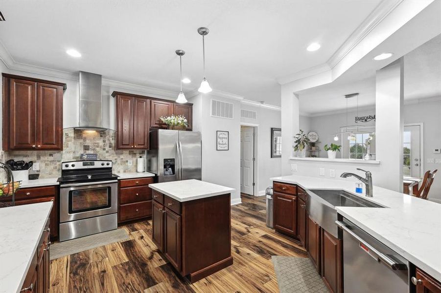 Kitchen featuring stainless steel appliances, tasteful backsplash, pendant lighting, and wall chimney exhaust hood