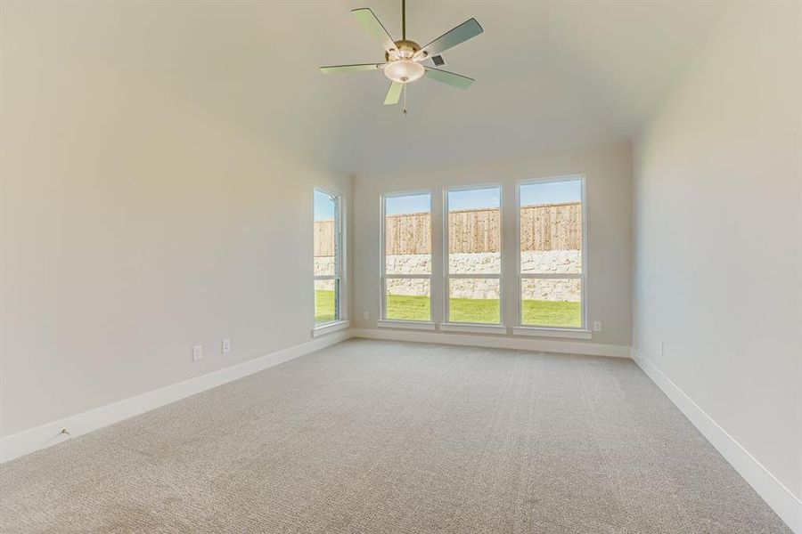 Unfurnished room featuring light carpet, a ceiling fan, and vaulted ceiling