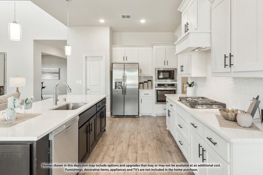 Kitchen with white cabinets, dark island, stainless steel appliances, and light wood floors