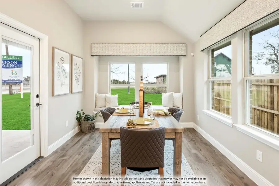 Bright dining area with vaulted ceiling, wood table, bench seating, and large windows overlooking a backyard.