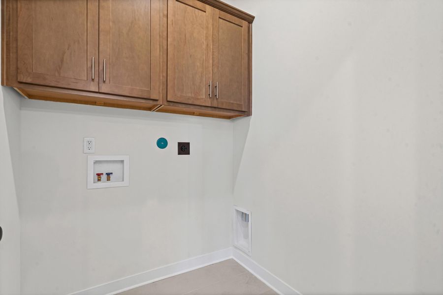 Laundry area featuring light-toned walls, wood-finish cabinetry with silver hardware, white trim, and necessary utility hookups Laundry area featuring light-toned walls, wood-finish cabinetry with silver hardware, white trim, and necessary utility hookups