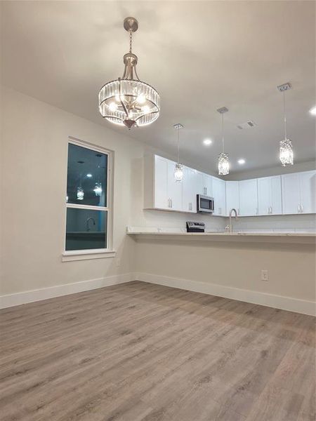 Glass chandelier hanging in the dinging room area and view of the breakfast bar.