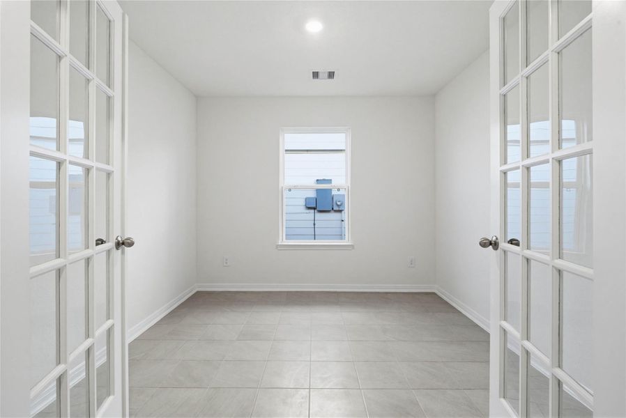 The Den is a versatile and additional living space that can be used as a home office, hobby or play room. It features French Doors, durable tile flooring, high ceilings, recessed lighting, neutral paint, and a large window.