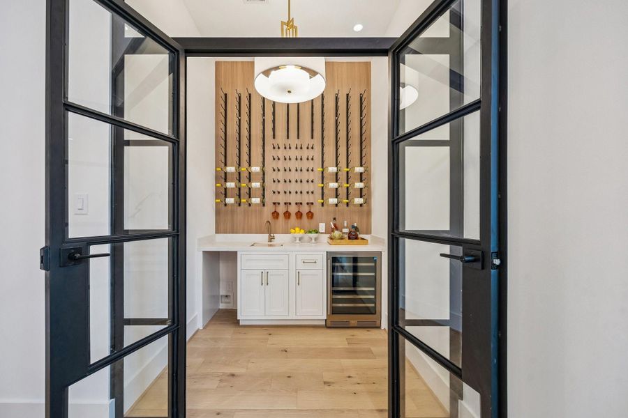 The Wine Grotto is entirely enclosed with the ability to add climate control. There is a 72 Bottle Wine Rack, Slab Quartz Counter, Kraus Stainless Steel Sink with a Single Handle Faucet In a Champagne Bronze Finish, Under-Counter Storage Cabinet, Zephyr Dual Zone Wine Cooler, Pre-Plumbing for an Ice-Maker and a Possini Euro Sundry 24" Pendant Light.