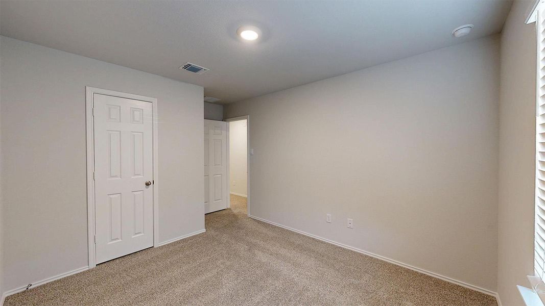 Unfurnished bedroom with light carpet and baseboards