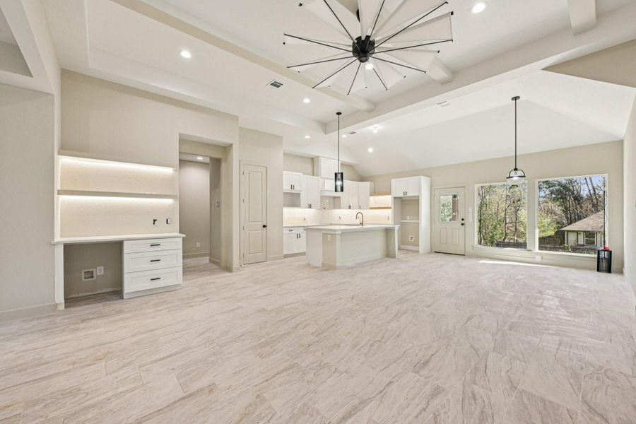 This open  area is illuminated by natural light from expansive windows and showcases elegant flooring. Ideal for entertaining and family gatherings.