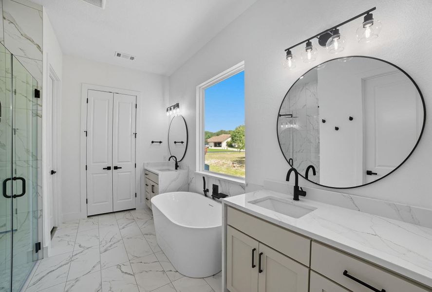 Full bath with a marble finish shower, light marble finish floors, a freestanding bath, and two vanities Full bath with a marble finish shower, light marble finish floors, a freestanding bath, and two vanities