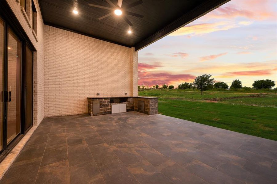 Patio terrace at dusk with area for grilling, ceiling fan, a patio area, and a lawn Patio terrace at dusk with area for grilling, ceiling fan, a patio area, and a lawn