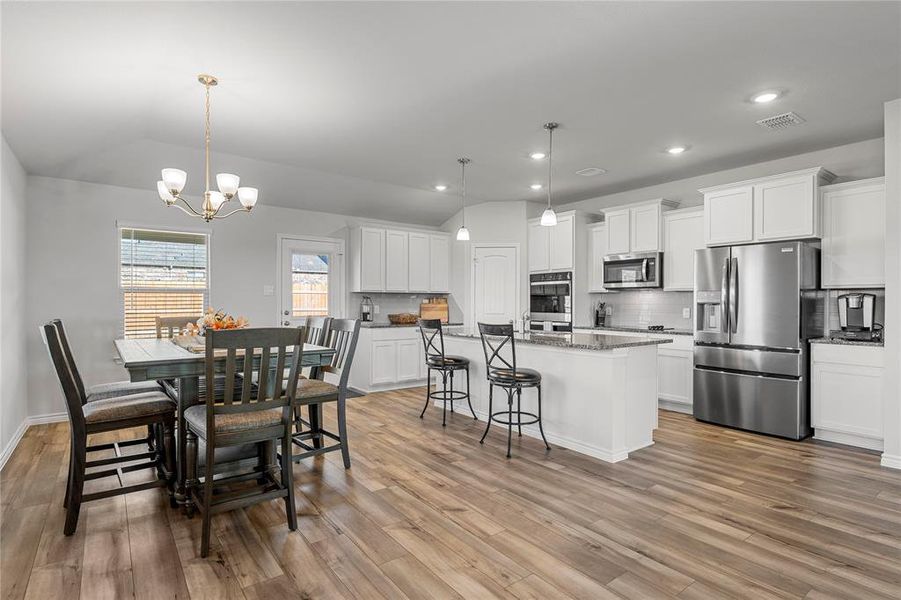 Dining room featuring lofted ceiling, a chandelier, light wood-type flooring, and recessed lighting