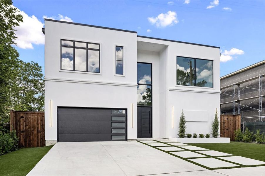 Modern home featuring stucco siding, a garage, and driveway Modern home featuring stucco siding, a garage, and driveway